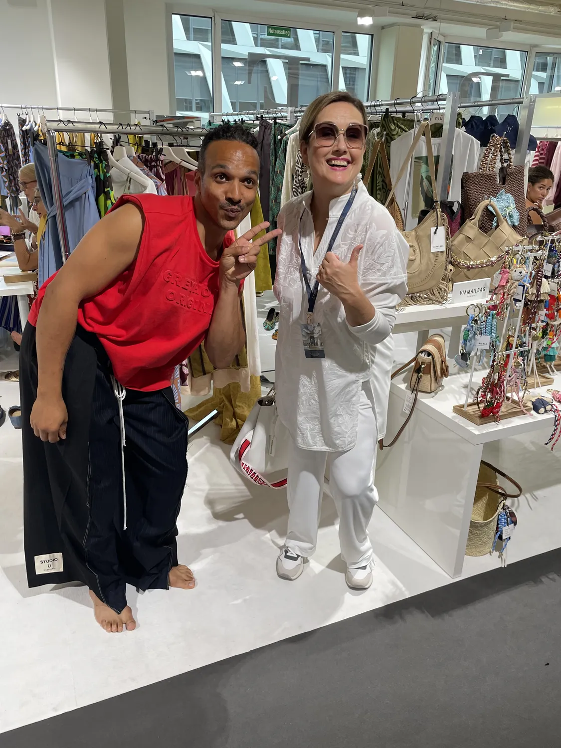 Abig-Moden - Modeboutique - Zwei Personen posieren ausgelassen in einer hell erleuchteten Bekleidungsboutique, umgeben von verschiedenen Kleidungsstücken und Accessoires.