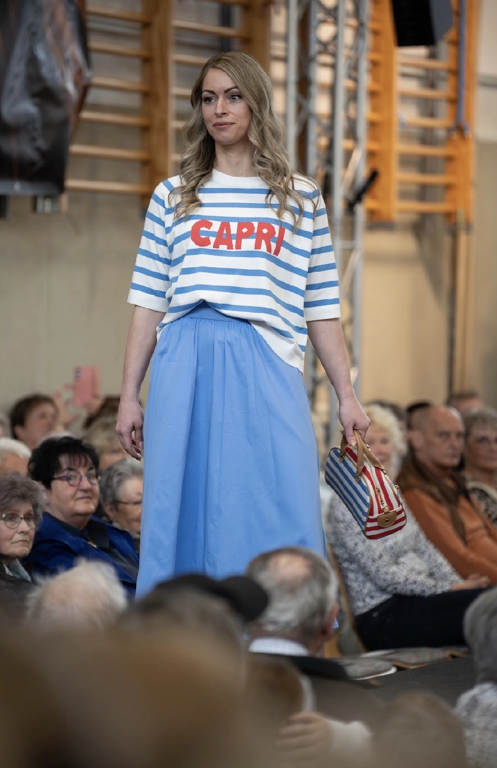 Abig-Moden - Modeboutique - Eine Frau in einem ganz in Weiß gekleideten Outfit stöbert in einem Modegeschäft an einem Ständer mit farbenfrohen Sommerkleidern und gemusterten Oberteilen.