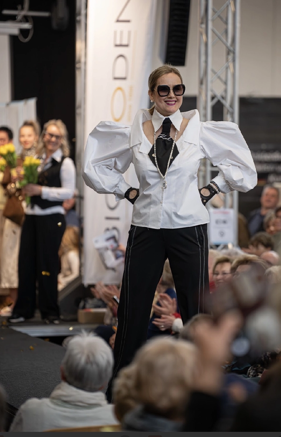 Abig-Moden - Modeboutique - Ein Model mit langen, lockigen Haaren posiert in einem weißen T-Shirt mit dem fettgedruckten schwarzen Schriftzug „LOVE ON TOP“ unter der Überschrift „10 DAYS“.
